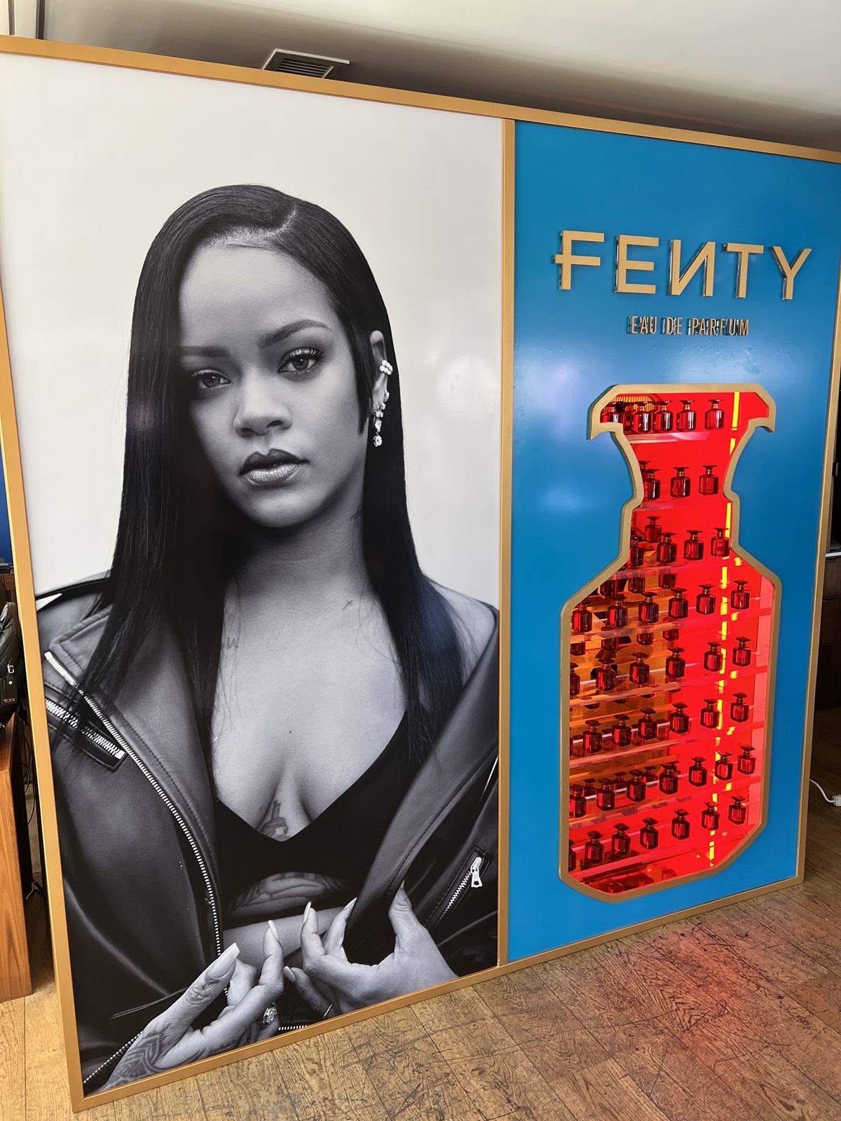 Framed fragrance display wall with an illuminated bottle cutout