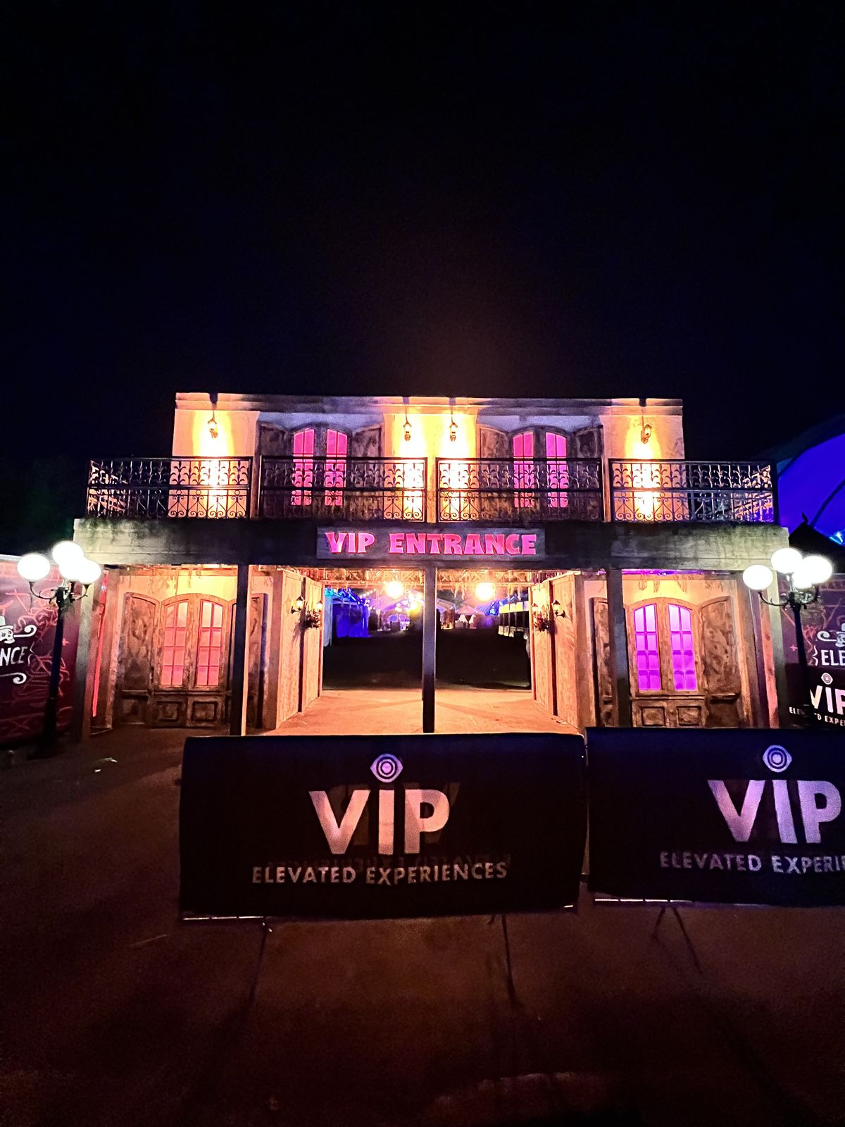 Two-story VIP entrance facade lit in amber and magenta at night